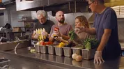 Four people preparing vegetables in a commercial kitchen.