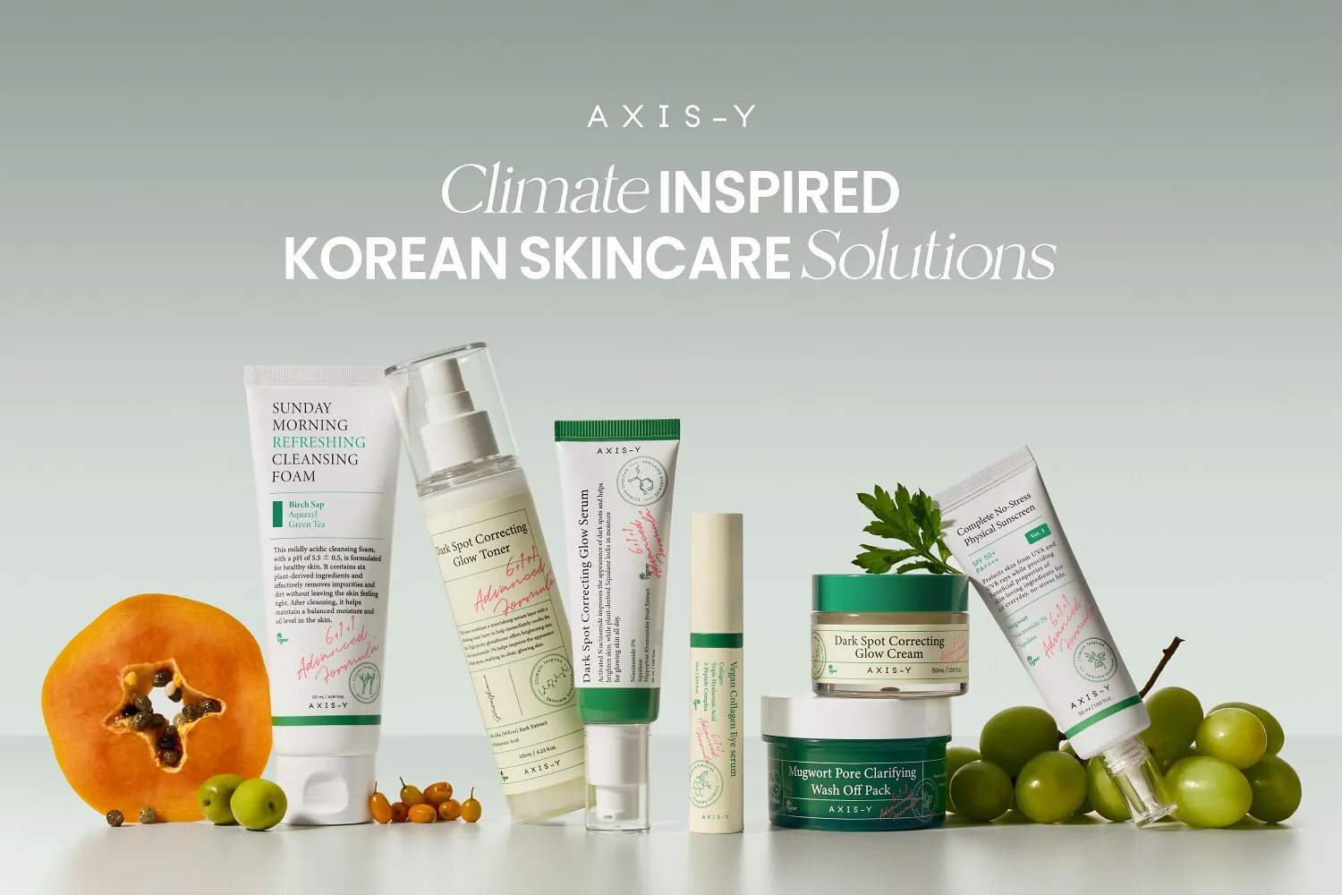 Axis-Y Korean skincare products arranged with papaya, green grapes and leaves on a pale green background