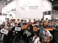 Group of attendees holding company signs and flags at the Startup Terrace exhibition booth.