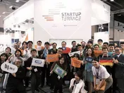 Group of attendees holding company signs and flags at the Startup Terrace exhibition booth.