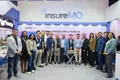 Group of businesspeople at the insureMO exhibition booth with a cake on a table