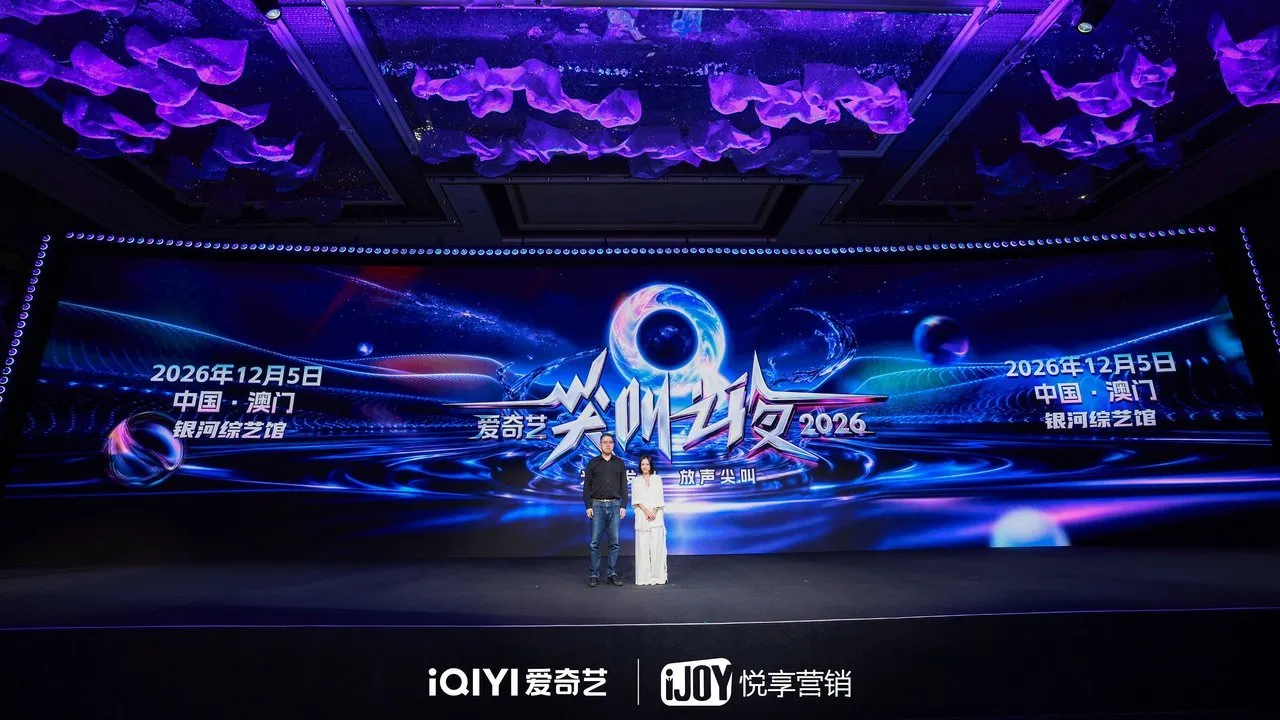 Two people stand before a large iQIYI promotional screen announcing a 2026 event in Macau.