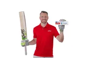 Man in red Anchor shirt holding a cricket bat and a toothpaste box.