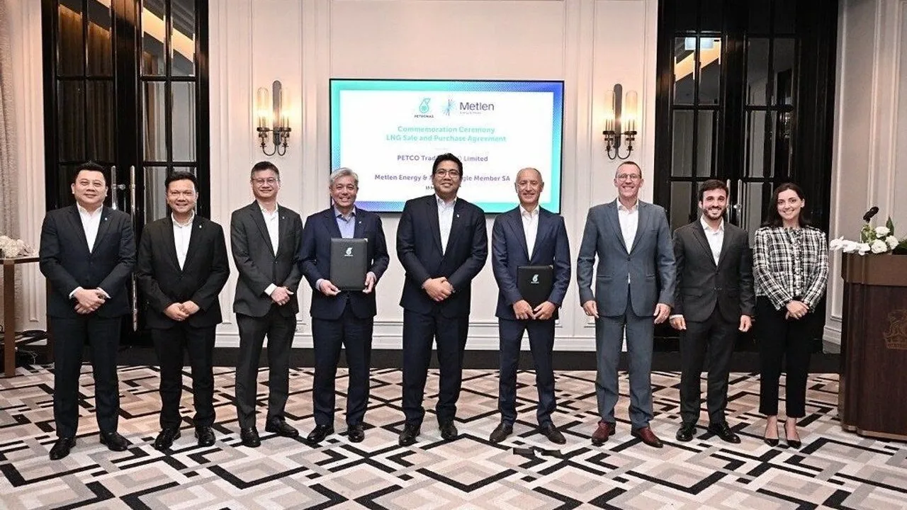 Nine people stand at an LNG sale and purchase agreement signing ceremony.