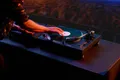 A DJ scratches a vinyl record on a turntable.