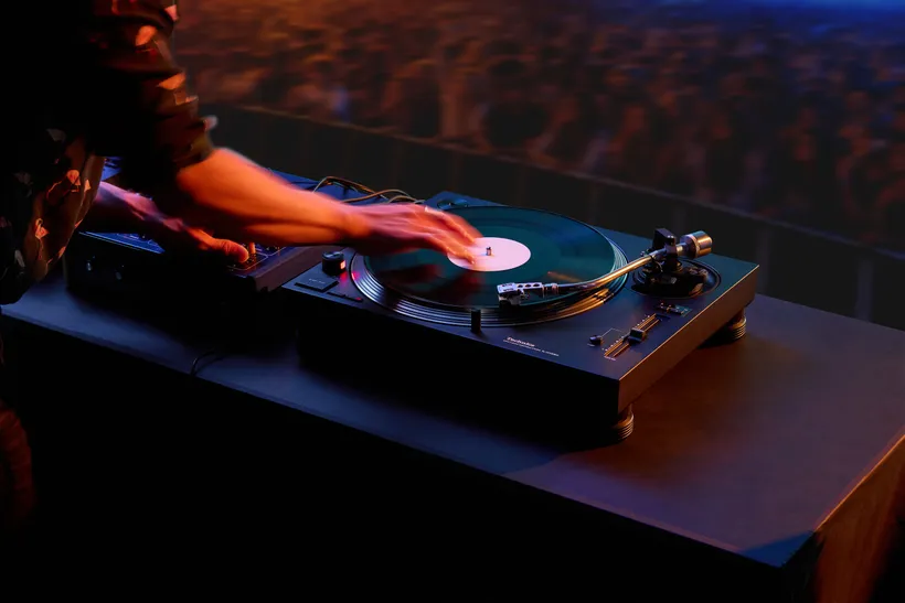 A DJ scratches a vinyl record on a turntable.