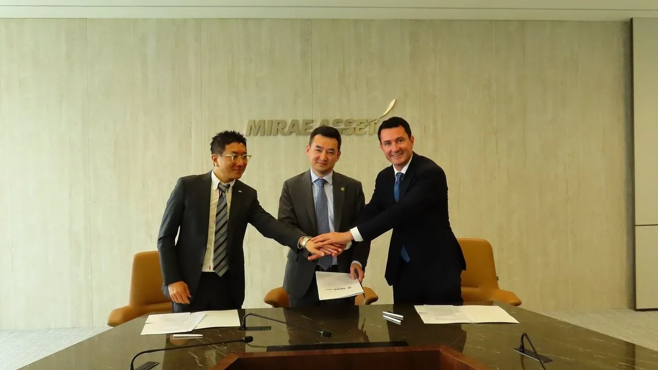 Three businessmen stack hands over a conference table with signed documents beneath a Mirae Asset sign.