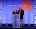 Ken and Elizabeth stand at a podium on the American Film Market stage.