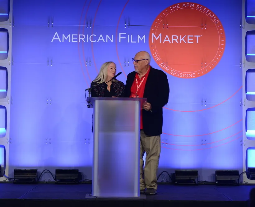 Ken and Elizabeth stand at a podium on the American Film Market stage.