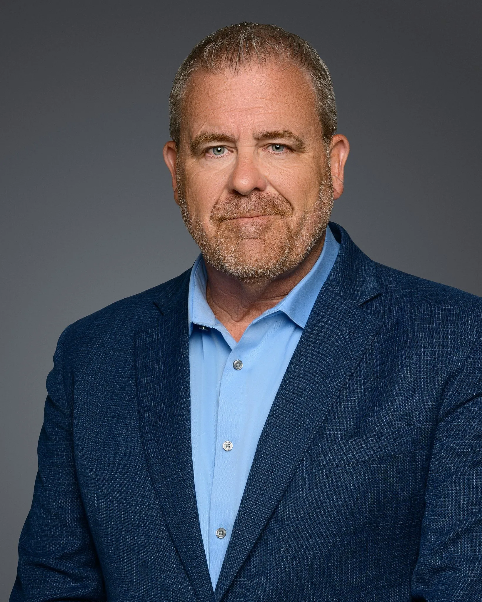 Jason Bradt in a blue blazer and light blue shirt against a gray background.