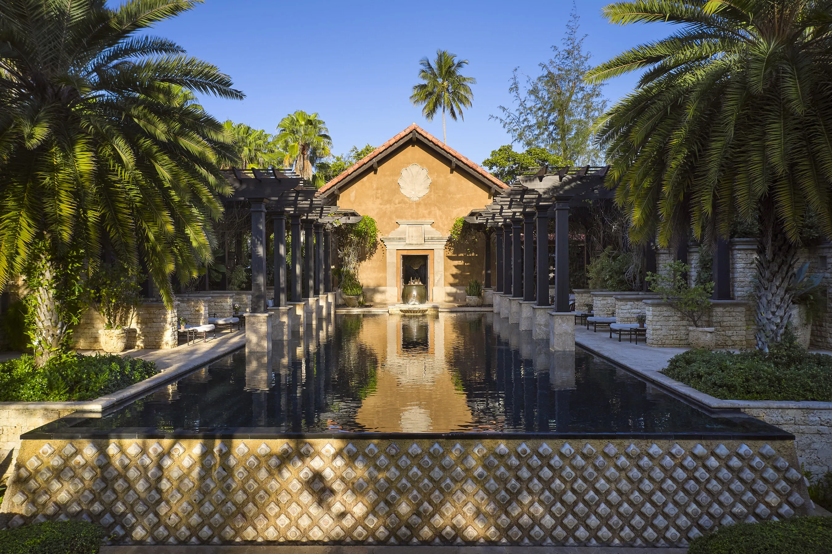 A long spa pool framed by palm trees and stone columns