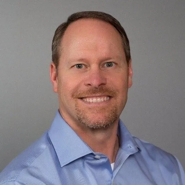 Scott Maupin wearing a light blue collared shirt against a gray background.