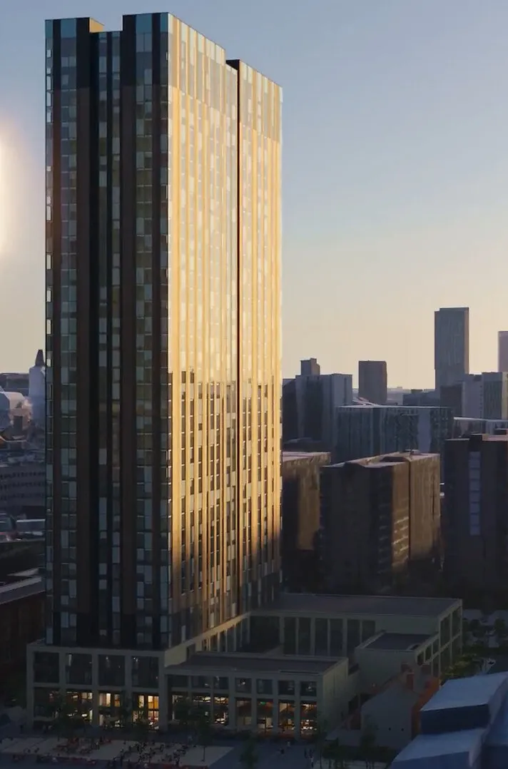 Tall glass high-rise tower lit by golden sunlight above surrounding city buildings.