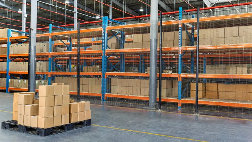 Boxes stacked on a pallet in a large warehouse with rows of storage racks.