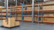 Boxes stacked on a pallet in a large warehouse with rows of storage racks.