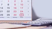 Calendar with a red-circled date beside a calculator and paperwork.