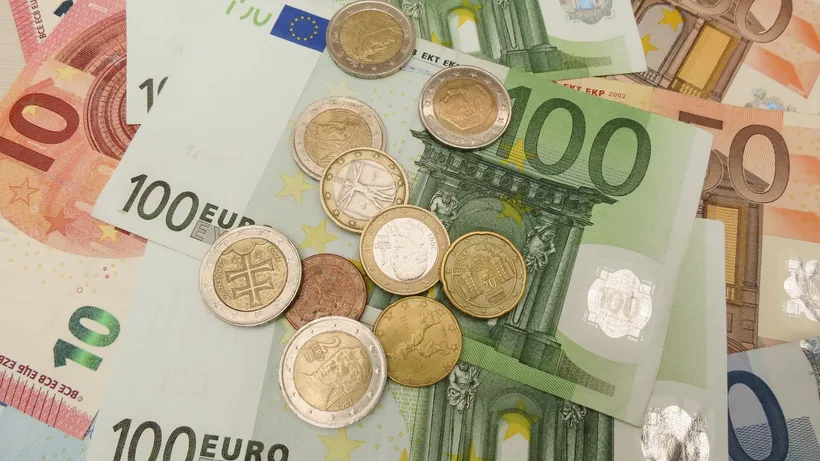 Euro banknotes and coins spread across a flat surface.