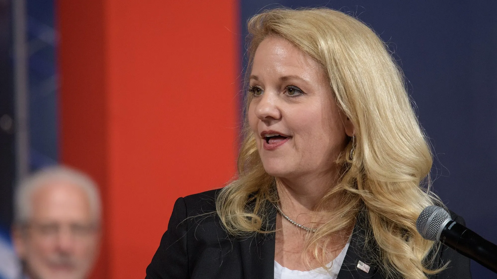 Gwynne Shotwell, president and chief operating officer of SpaceX, speaking at a microphone at a NASA event in Houston in 2018